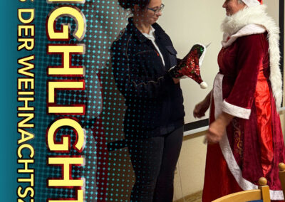 Weihnachtsfrau von aus der MITTE überreicht einer Mitarbeiterin eine Weihnachtsmütze mit Scheck